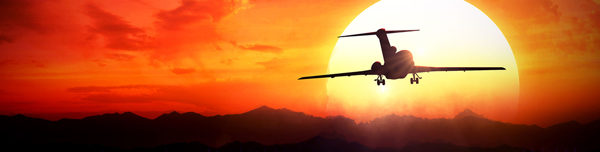 Image of an aeroplane flying into the sunset