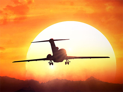 An aeroplane taking off into a sunset