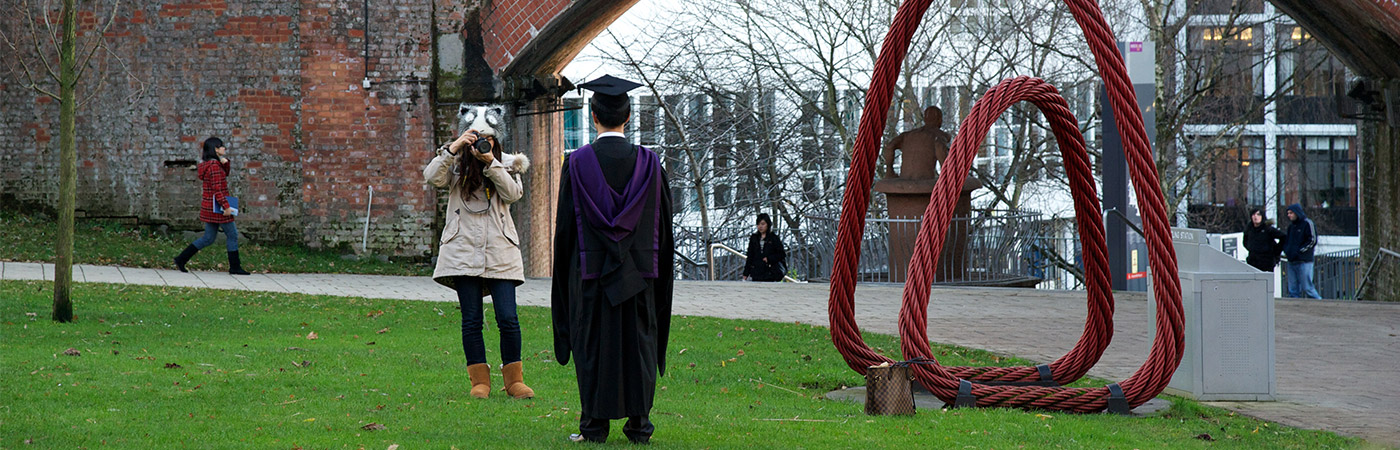 Woman taking a photo of graduate in cap and gown